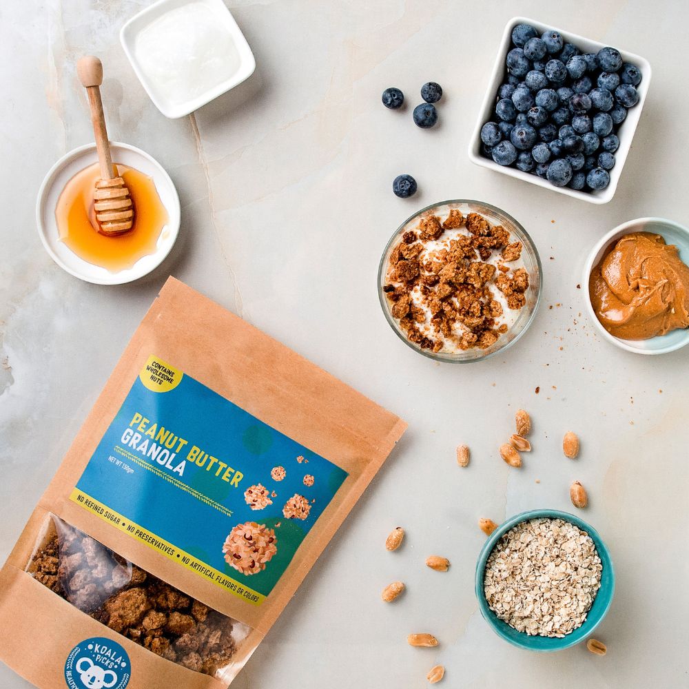 Peanut butter granola package with granola, blueberries, honey, and peanut butter on a light surface.