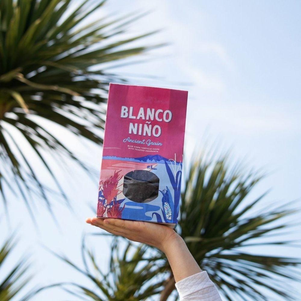Person holding a 'Blanco Niño' package against a palm tree background