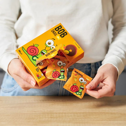 Person holding a box of Bob Snail candy with one piece held up.