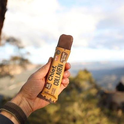 A hand holding a chocolate-covered collagen bar wrapper labeled 'Chief Collagen' against a blurred outdoor mountain landscape.
