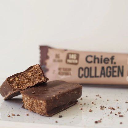 A close-up of a chocolate collagen bar, with one bar broken in half to show the textured collagen-rich interior, and the wrapper blurred in the background. The wrapper is beige with dark brown text reading 'Chief.