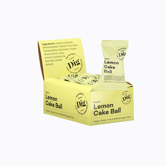 A box of Dig Naturally Lemon Cake Ball vegan snacks, showing the yellow packaging, a single wrapped ball, and several unwrapped cake balls inside the box against a white background.