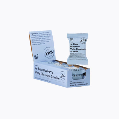 A box of Dig The Difference No-Bake Blueberry White Chocolate Crumble snack sticks, with one individual stick pack standing upright in front of the open display box on a white background.