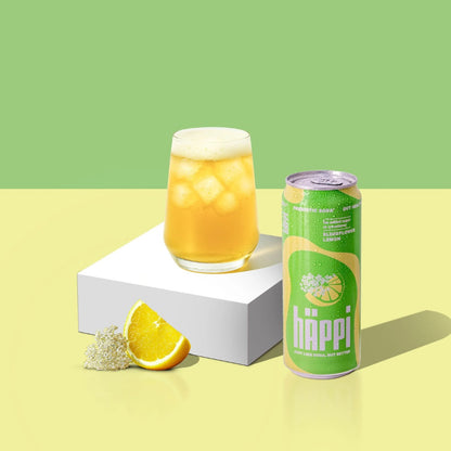 Happi can and glass of orange drink with lemon wedge on a green and yellow gradient background