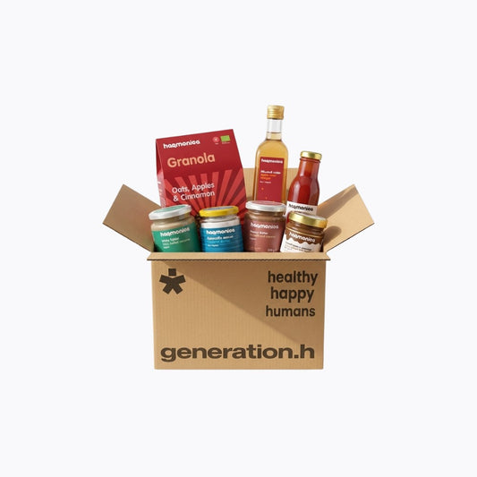 Cardboard box from 'generation.h' with health products including granola and sauces on a white background