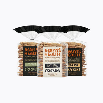 Three bags of Keen of Health crackers arranged together on a light gray background. The center bag is labeled Natural Crackers, flanked by Thyme Crackers on the left and Black Rice Crackers on the right.
