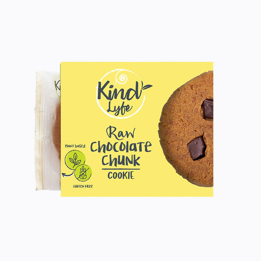 A package of Kindly Lyfe Raw Chocolate Chunk Cookie, featuring a bright yellow box with a photo of a chocolate chip cookie on the right side and a single wrapped cookie packet peeking out from the left, set against a plain white background.