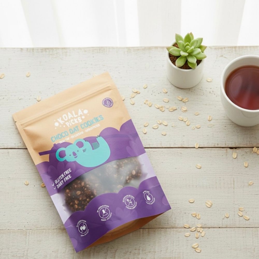 Packaged food product on a wooden surface with a cup of tea and a small plant.
