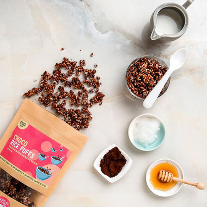 Choco rice puffs with packaging, milk, honey, and a spoon on a marble surface