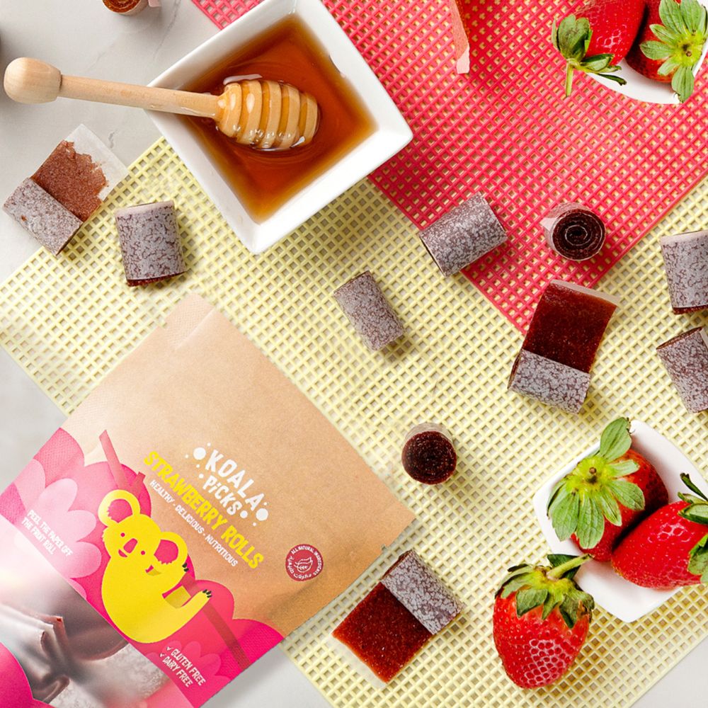 Kola Pops strawberry rolls packaging with honey, strawberries, and a dipper on a colorful background.