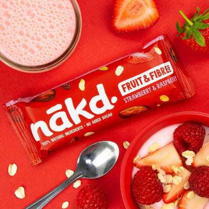 Nakd Fruit & Fibre strawberry and raspberry bar on a red background with a bowl of yogurt and fruit.