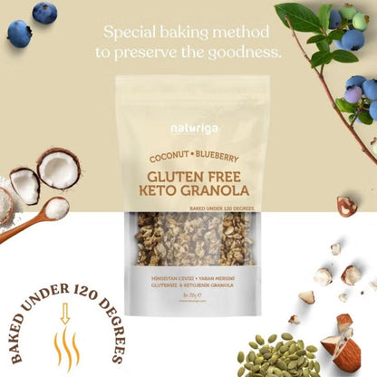 A stand-up pouch of Naturiga Coconut Blueberry Gluten Free Keto Granola centered on a beige background, surrounded by blueberries, nuts, seeds, and text highlighting a special baking method and baked under 120 degrees.