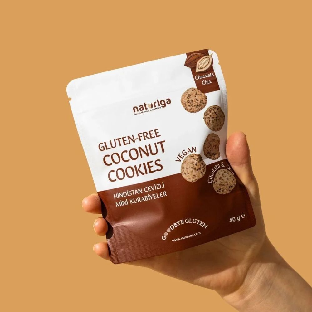 Hand holding a package of gluten-free coconut cookies with a brown background