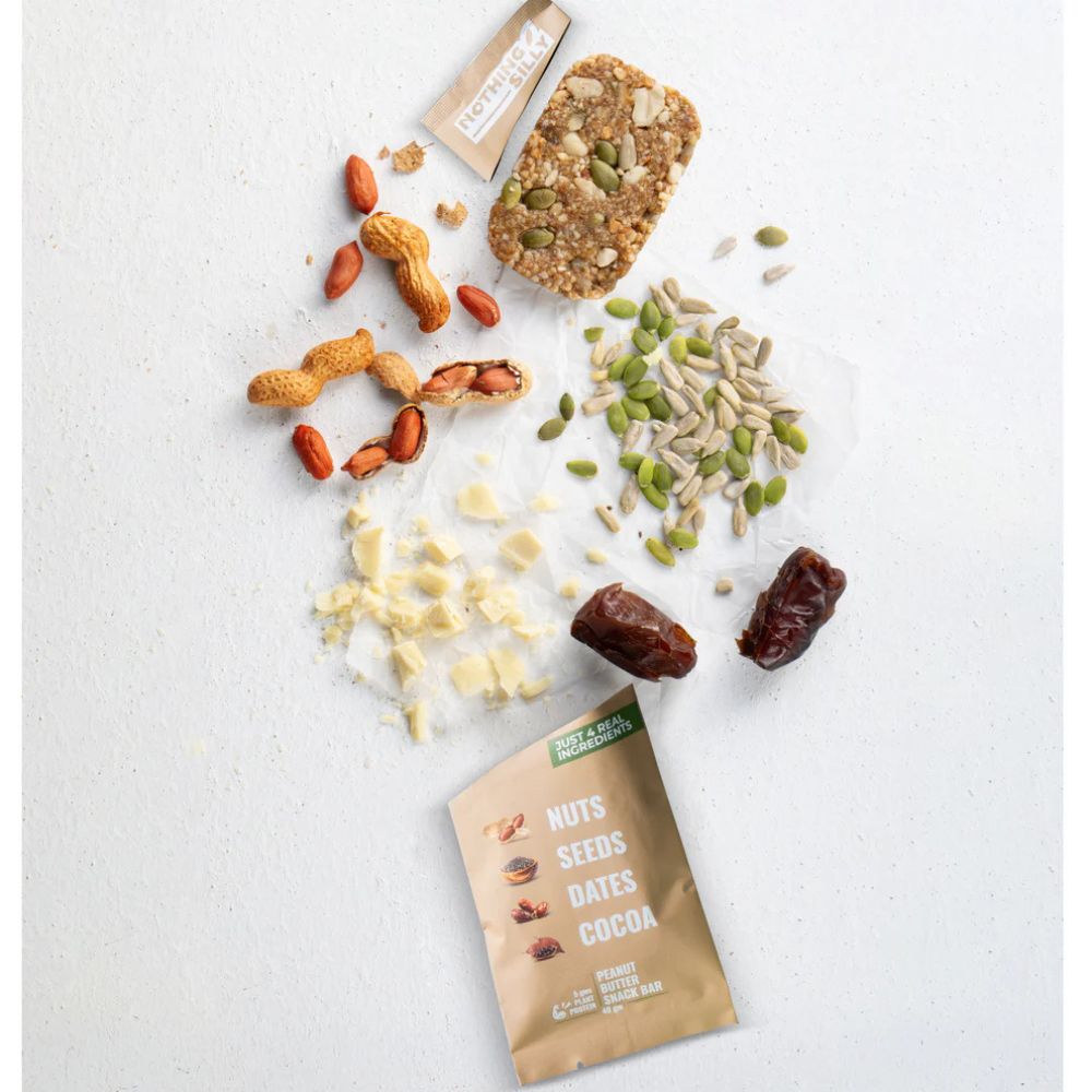 Nuts, seeds, dates, and cocoa powder on a white surface with a package labeled 'Nuts Seeds Dates Cocoa'.