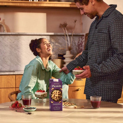 Man and woman in a kitchen with Plenish cashew packaging on the table.