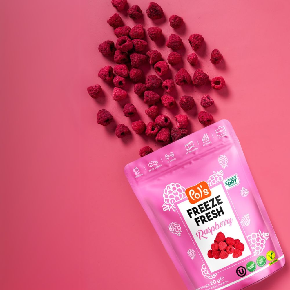 Pink package of freeze-dried raspberries with fresh raspberries on a pink background