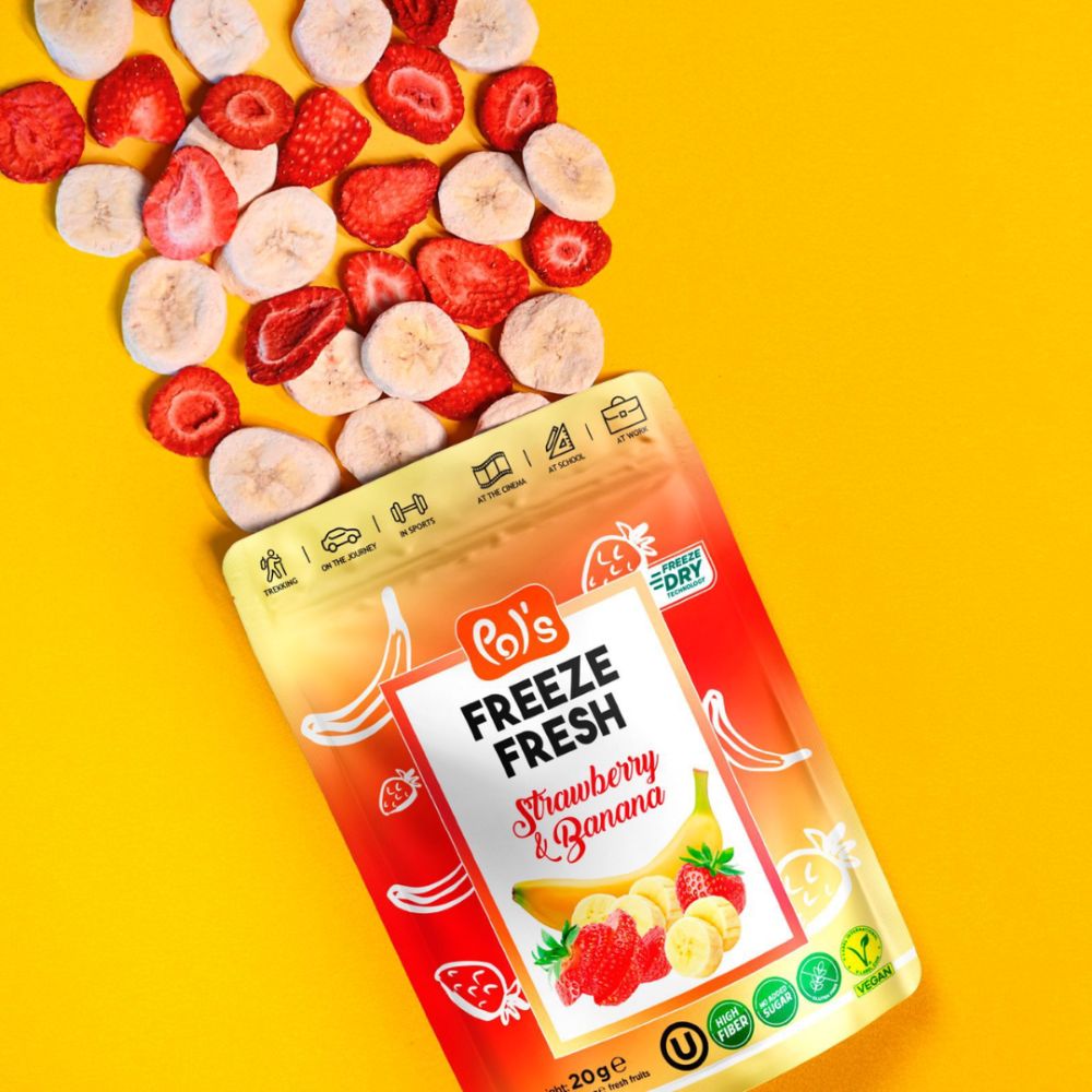 A stand-up pouch of Bo's Freeze Fresh Strawberry & Banana frozen fruit mix spilling out onto a bright yellow background, with sliced strawberries and bananas scattered above it.