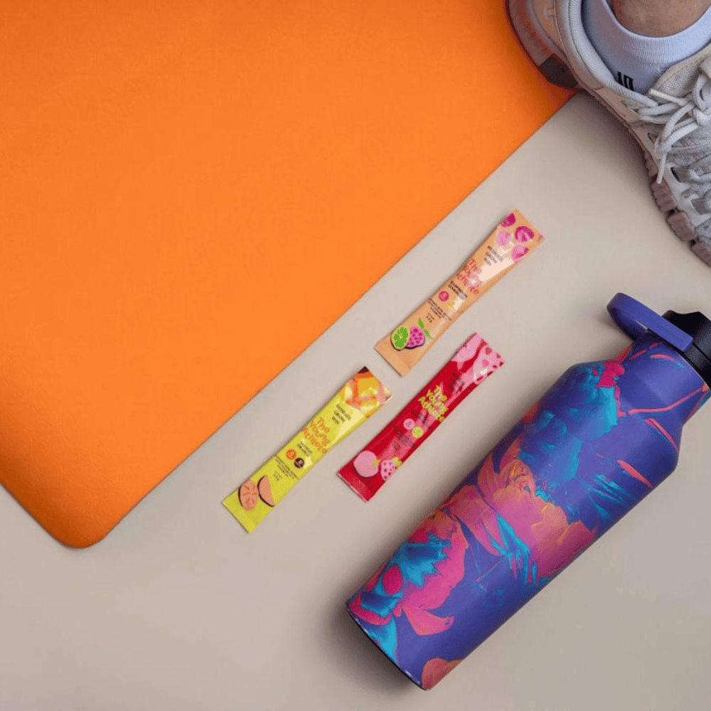 Colorful water bottle and fruit gummies on a beige and orange surface