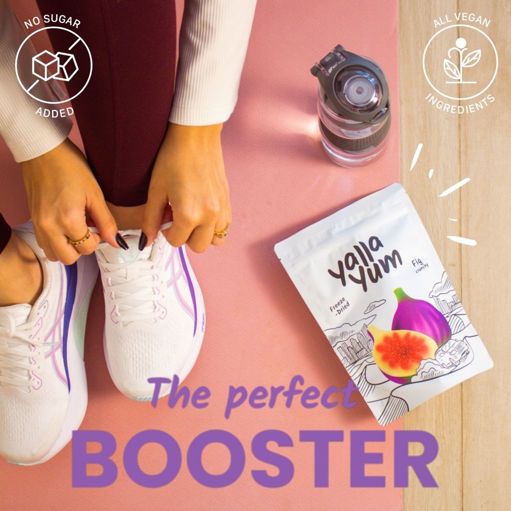 Person tying shoelaces with a Yalla Yum snack package and water bottle on a pink surface.