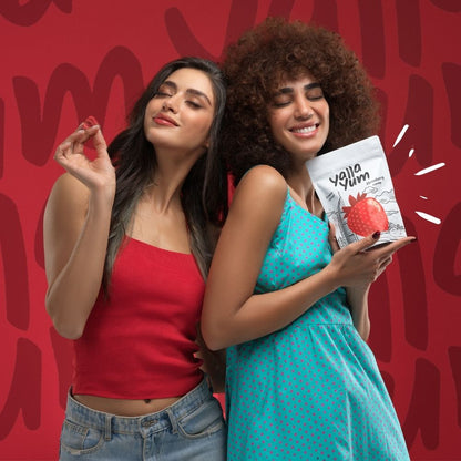 Two women holding Yello Gum packages against a red background