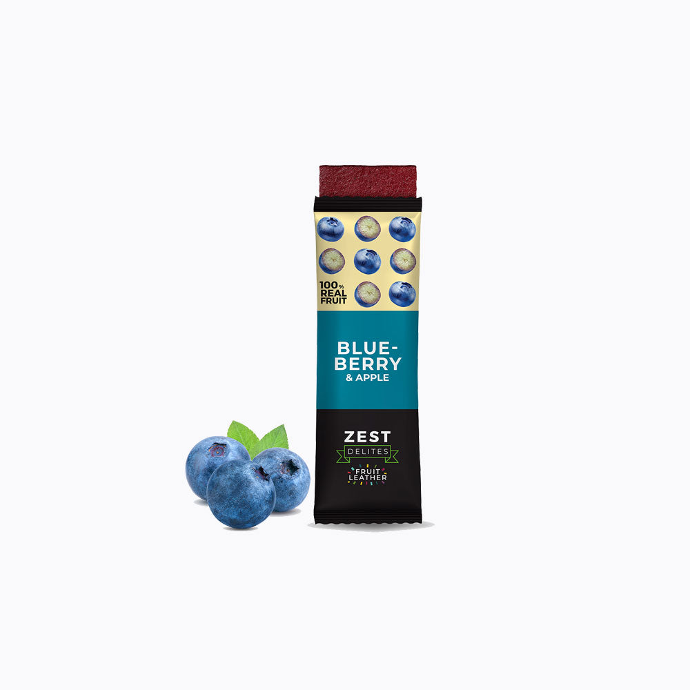 A 24-pack display box of Zest Zestix Mango Apple Based Dried Fruit Bars, featuring multiple individually wrapped bars fanned out from a black cardboard tray with fruit illustrations and a few fresh mangoes and an apple on a white background.