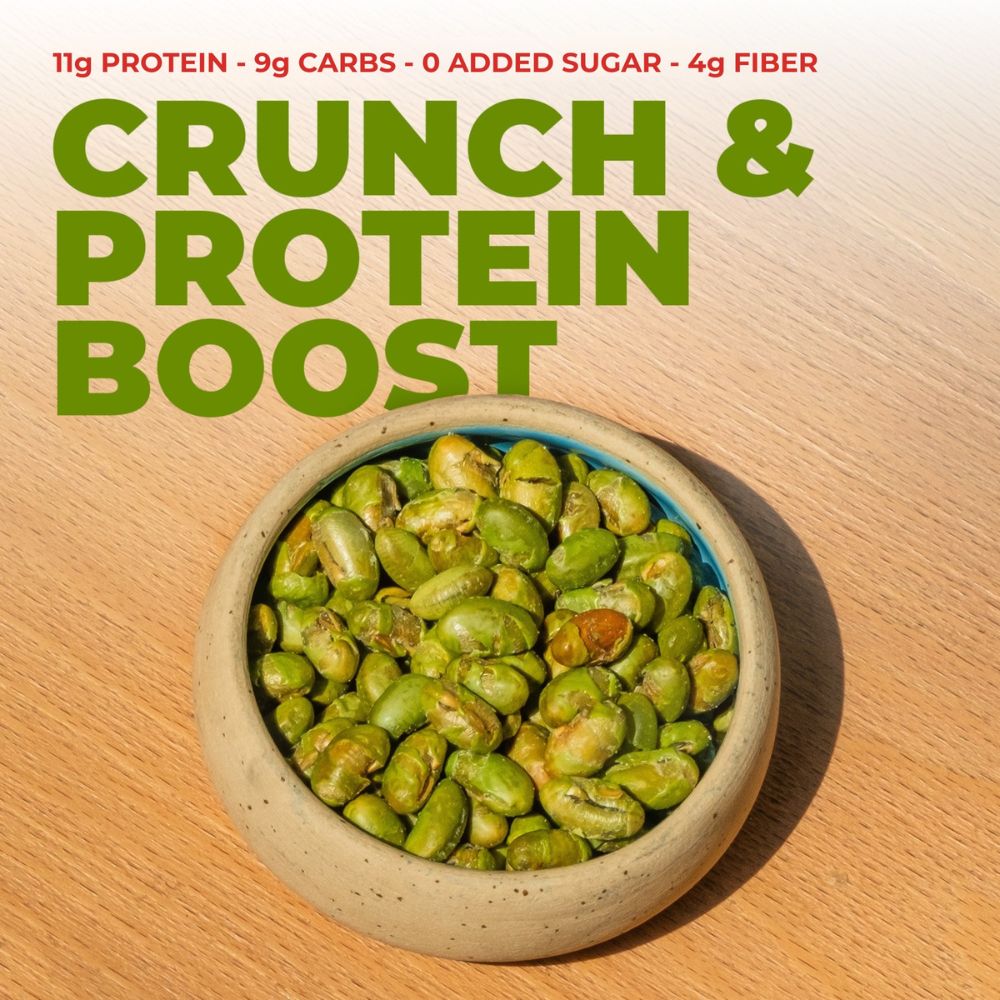A bowl of green protein clusters on a light wood surface with bold text reading 'CRUNCH & PROTEIN BOOST' and smaller text noting '11g PROTEIN - 9g CARBS - 0 ADDED SUGAR - 4g FIBER'.