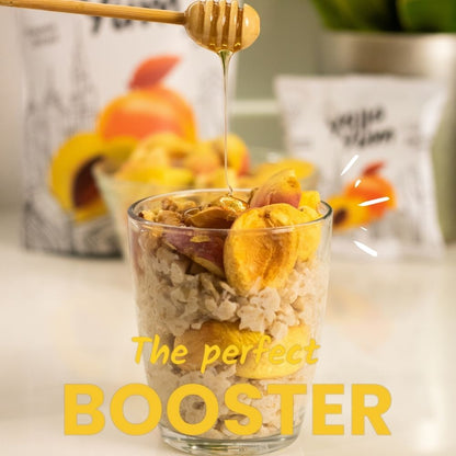 Glass of cereal with dried fruits and honey being drizzled over it, with text 'The perfect BOOSTER' on a blurred background.